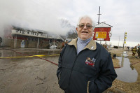 Ernie Edwards pózuje před hořící budovou